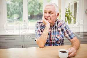 Thoughtful senior man sitting at table