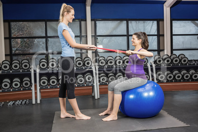 Trainer and pregnant woman using a resistance band