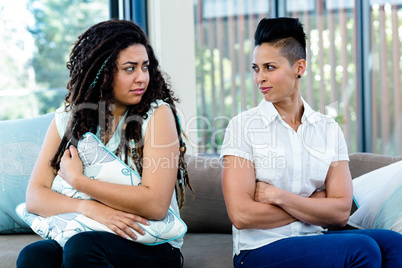 Unhappy lesbian couple sitting on sofa