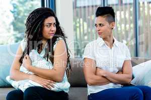 Unhappy lesbian couple sitting on sofa