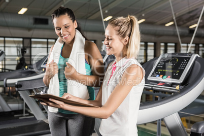 Smiling trainer showing clipboard to woman