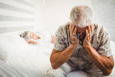 Frustrated senior man sitting on bed