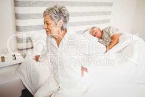 Senior woman suffering from backache sitting on bed