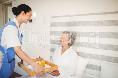 Nurse serving breakfast to senior woman