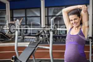 Smiling pregnant woman stretching her amrs