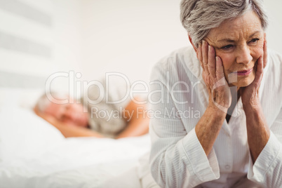 Worried senior woman sitting on bed