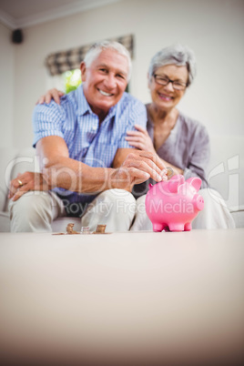 Senior man putting coins in piggy bank