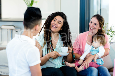 Three woman sitting on sofa with a baby