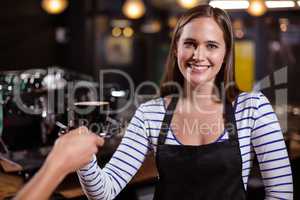 Pretty barista giving coffee to customer and smiling at the came
