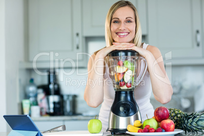 Pretty blonde woman preparing a smoothie