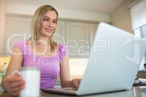 Pretty blonde woman having coffee and using laptop