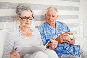 Senior couple reading magazine in bedroom