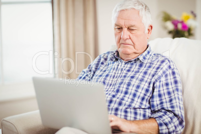 Senior man using laptop in living room