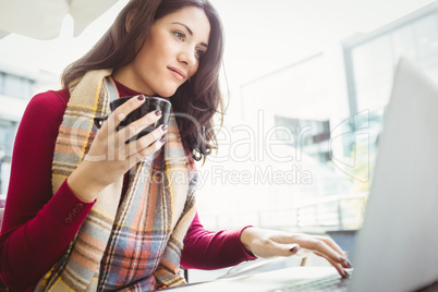 Woman using her laptop and drinking coffee