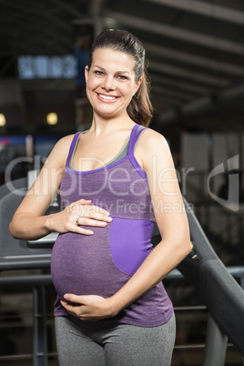 Smiling pregnant woman touching her belly