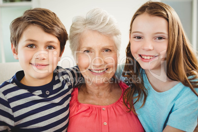 Grandmother and grandchildren sitting together on sofa