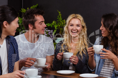 Smiling friends talking and enjoying coffee