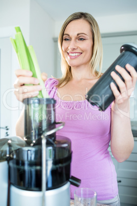 Blonde woman preparing a smoothie in the kitchen