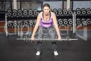 Determined woman lifting barbell