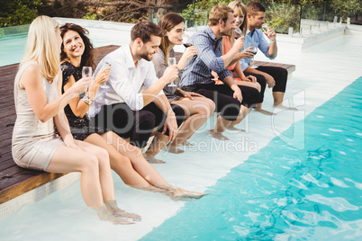 Young people sitting by swimming pool