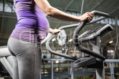 Pregnant woman standing on a fitness machine