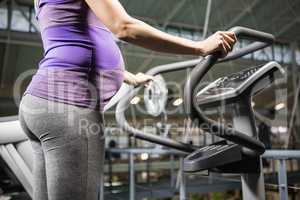 Pregnant woman standing on a fitness machine