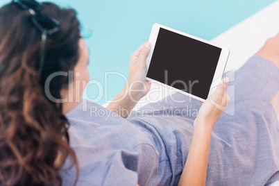 Young woman using digital tablet near poolside