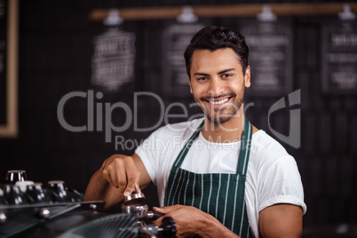 Smiling barista preparing coffee with a machine