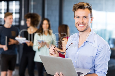 Portrait of man holding a laptop and smiling