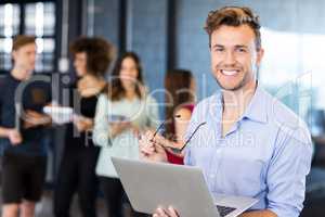 Portrait of man holding a laptop and smiling