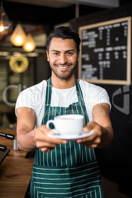 Smiling barista holding coffee