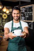 Smiling barista holding coffee