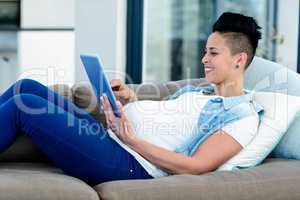 Pregnant woman relaxing on sofa with her digital tablet