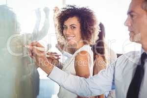 Businesspeople writing on white board