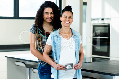 Pregnant lesbian couple holding a sonography report