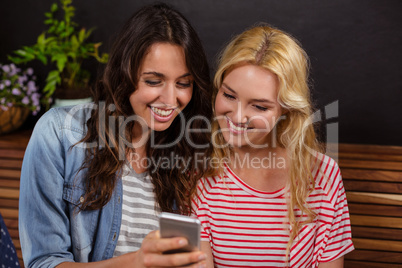 Smiling friends watching a smartphone together