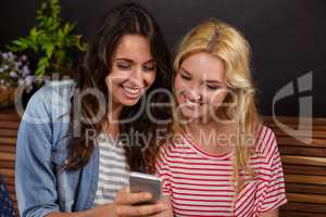 Smiling friends watching a smartphone together