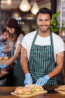 Smiling barista cutting sandwich