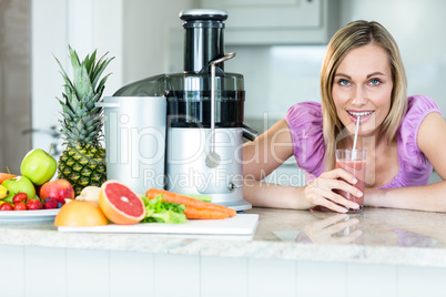 Blonde woman drinking a smoothie in the kitchen