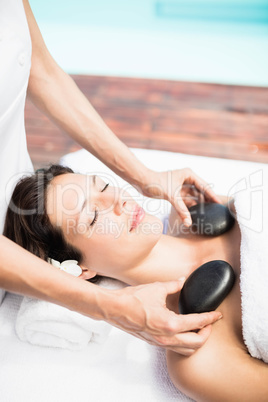 Woman receiving a hot stone massage from masseur