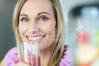 Pretty blonde woman drinking her homemade smoothie