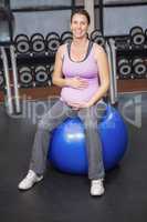Determined woman sitting fitness ball and touching belly