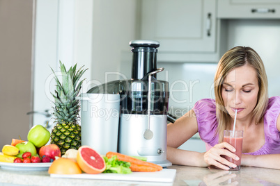 Blonde woman drinking a smoothie in the kitchen