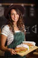 Smiling barista holding sandwiches