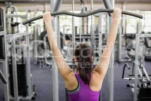 Fit woman using weight machine