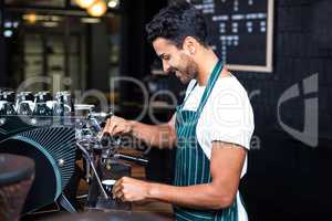 Smiling waiter making cup of coffee