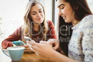 Friends using smartphone and having coffee