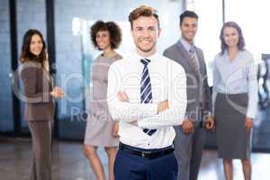 Businessman smiling at camera while his colleagues posing in bac