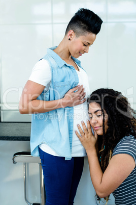 Woman listening to pregnant partners stomach