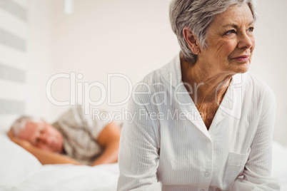 Worried senior woman sitting on bed